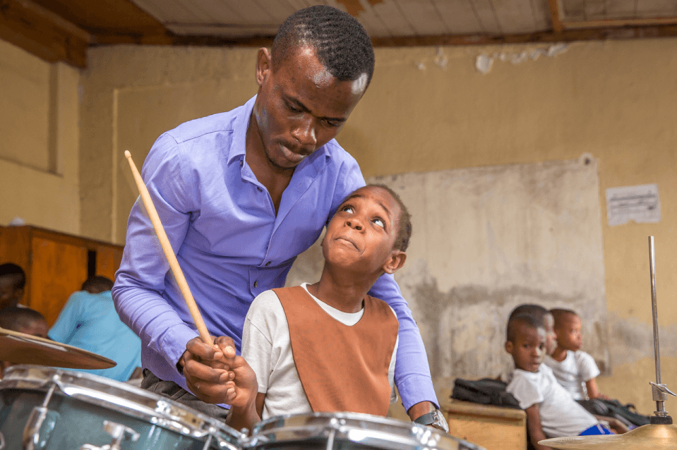 A Teacher and a kid playing drums